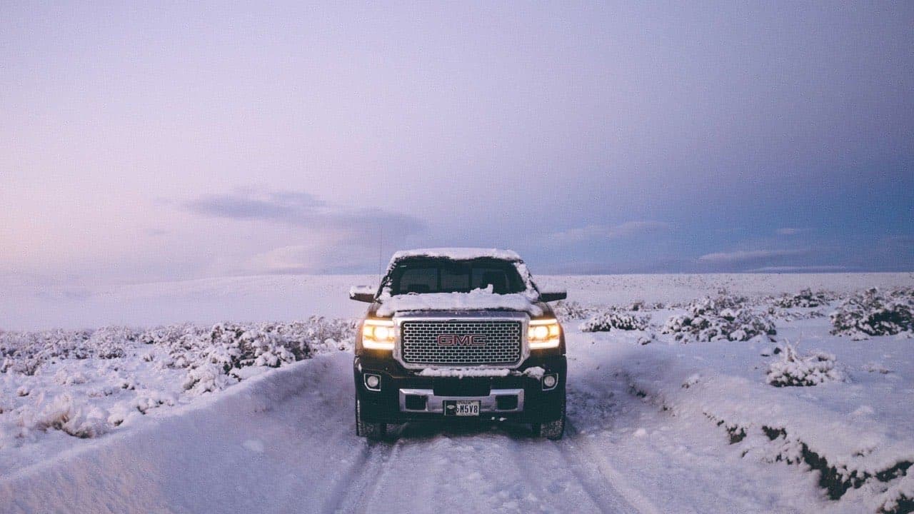 Camion GMC Sierra roulant sur une route enneigée au Québec, illustrant les conditions hivernales qui accélèrent l'usure et la corrosion des véhicules commerciaux